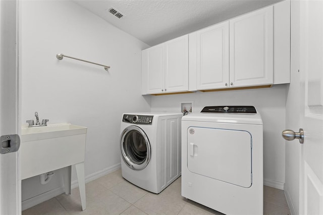 2432 Riviera Ln, Minneola, FL 34715 - laundry room featuring independent washer and dryer, cabinet space, light tile patterned floors, and a textured ceiling