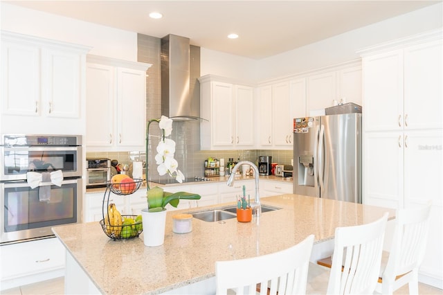 1545 Fairview Cir, Reunion, FL 34747 - kitchen featuring stainless steel appliances, wall chimney exhaust hood, a kitchen island with sink, white cabinets, and recessed lighting