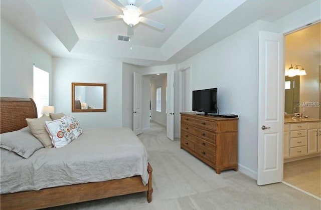 1545 Fairview Cir, Reunion, FL 34747 - bedroom featuring light carpet, a tray ceiling, connected bathroom, and a ceiling fan