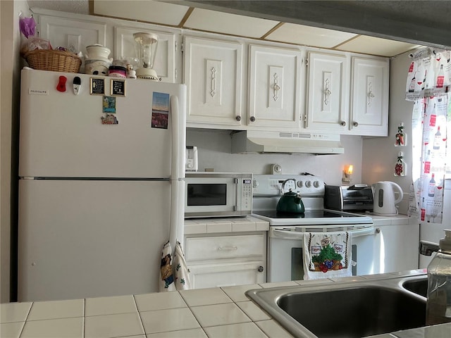 1409 Oak Pl Unit F, Apopka, FL 32712 - kitchen with white appliances, tile counters, under cabinet range hood, and white cabinetry