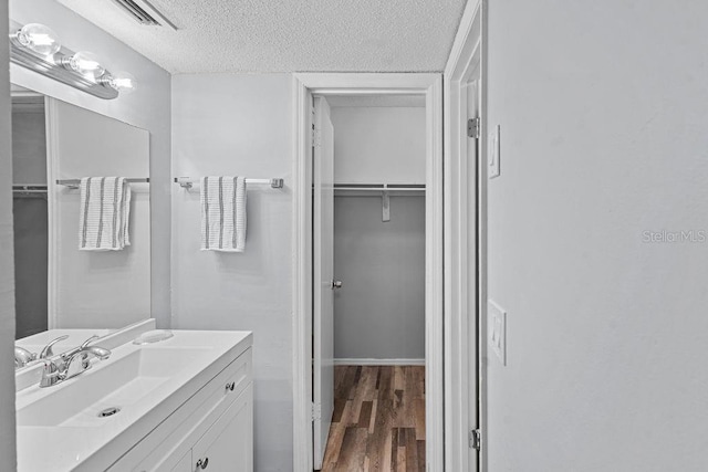 2517 Caper Ln Unit 207, Maitland, FL 32751 - bathroom featuring a textured ceiling, vanity, wood finished floors, and a walk in closet