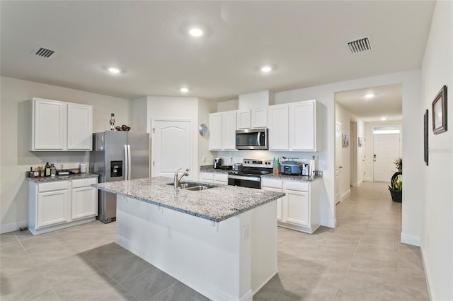 5808 Arboretum St, Saint Cloud, FL 34771 - kitchen with stainless steel appliances, a center island with sink, light stone countertops, white cabinetry, and recessed lighting