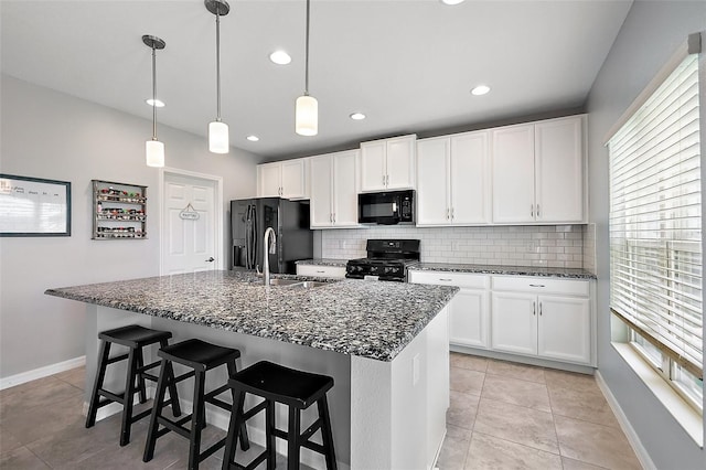 1292 Cavender Creek Rd, Minneola, FL 34715 - kitchen featuring black appliances, tasteful backsplash, white cabinetry, a kitchen island with sink, and dark stone counters