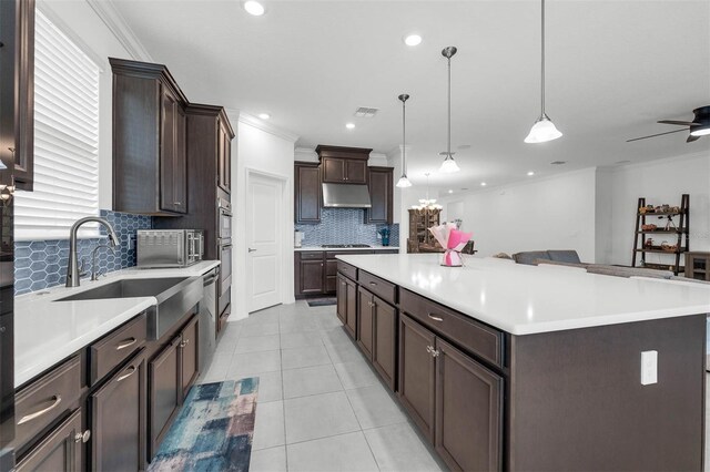 1593 Osprey View Dr, Apopka, FL 32703 - kitchen with under cabinet range hood, decorative backsplash, gas stovetop, dark brown cabinetry, and a center island