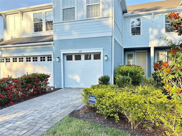 4171 Via Sienna Cir, Sarasota, FL 34243 - view of property with an attached garage, decorative driveway, a shingled roof, and board and batten siding