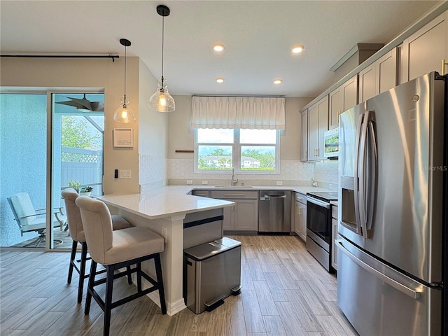 4171 Via Sienna Cir, Sarasota, FL 34243 - kitchen featuring stainless steel appliances, a peninsula, a kitchen breakfast bar, gray cabinetry, and decorative backsplash