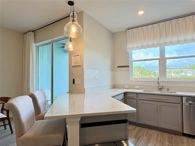 4171 Via Sienna Cir, Sarasota, FL 34243 - kitchen featuring gray cabinetry, stainless steel dishwasher, light wood-style floors, decorative backsplash, and a peninsula