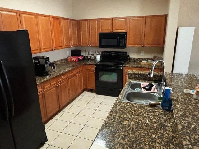 2536 Lancien Ct Unit 5, Orlando, FL 32826 - kitchen with black appliances, light tile patterned floors, and brown cabinets