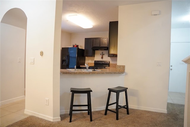 3569 Seneca Club Loop Unit 13, Orlando, FL 32808 - kitchen featuring black appliances, a breakfast bar area, a peninsula, light countertops, and light carpet