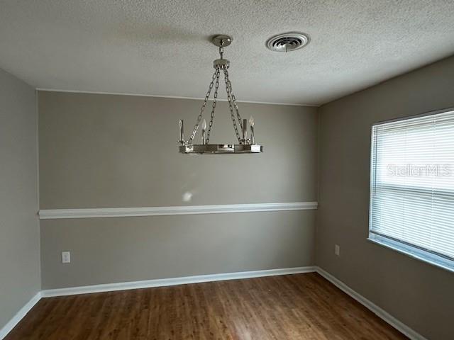 4732 Luce Rd, Lakeland, FL 33813 - spare room featuring wood finished floors, a chandelier, and a textured ceiling