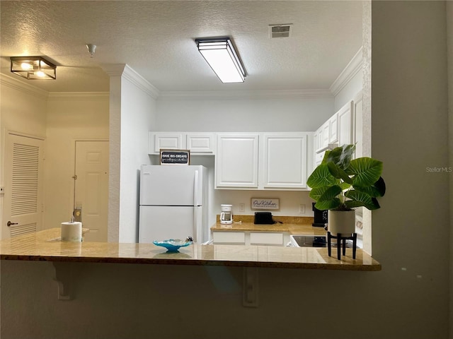 8010 Tuscany Way Unit 3102, Davenport, FL 33896 - kitchen with freestanding refrigerator, a breakfast bar area, white cabinetry, ornamental molding, and light stone counters