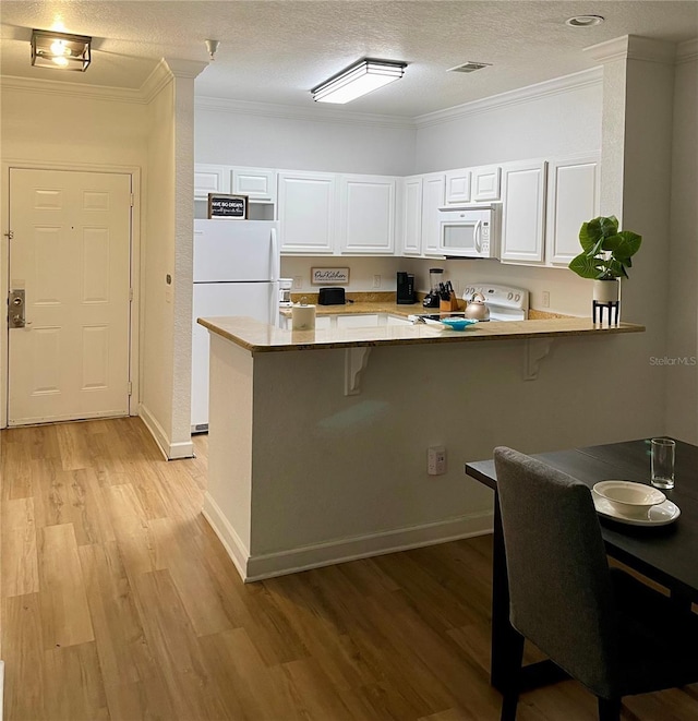 8010 Tuscany Way Unit 3102, Davenport, FL 33896 - kitchen featuring white appliances, a peninsula, white cabinets, a breakfast bar, and ornamental molding