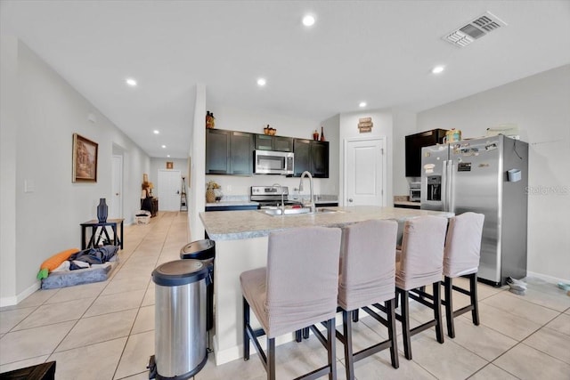 145 Piave St, Haines City, FL 33844 - kitchen featuring appliances with stainless steel finishes, light countertops, light tile patterned floors, a kitchen bar, and recessed lighting