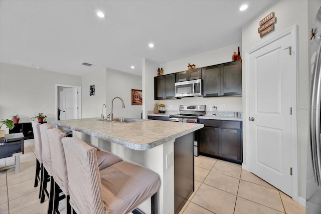 145 Piave St, Haines City, FL 33844 - kitchen featuring stainless steel appliances, a breakfast bar area, light countertops, light tile patterned floors, and a center island with sink
