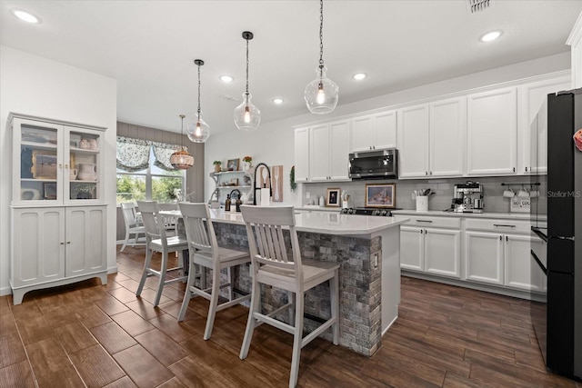 922 Grazie Loop, Davenport, FL 33837 - kitchen with stainless steel microwave, light countertops, recessed lighting, tasteful backsplash, and a center island with sink