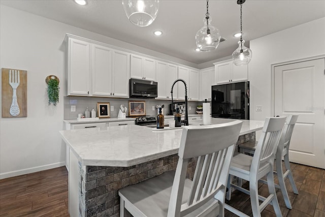 922 Grazie Loop, Davenport, FL 33837 - kitchen with stainless steel microwave, refrigerator, dark wood-style floors, white cabinets, and recessed lighting
