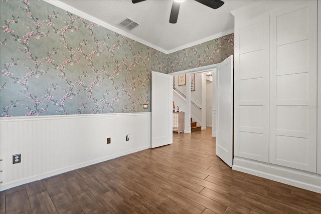 922 Grazie Loop, Davenport, FL 33837 - unfurnished bedroom with wainscoting, dark wood-type flooring, wallpapered walls, ornamental molding, and ceiling fan