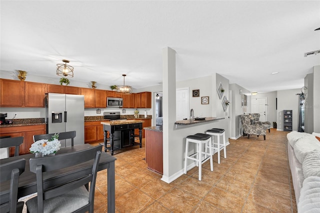 1224 Blackwater Pond Dr, Orlando, FL 32828 - kitchen featuring appliances with stainless steel finishes, open floor plan, a kitchen bar, and brown cabinetry