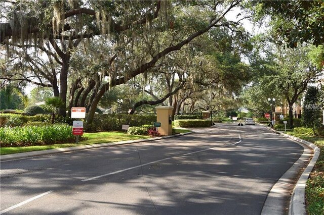 6214 Stevenson Dr Unit 208, Orlando, FL 32835 - view of asphalt road with curbs, view of scattered trees, and a gated entry