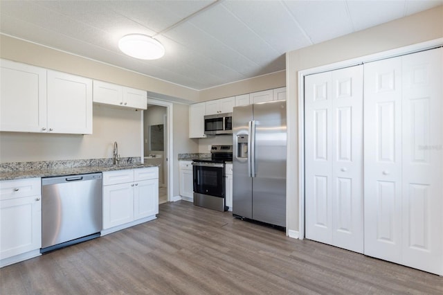 3850 11th Ave S, Saint Petersburg, FL 33711 - kitchen featuring appliances with stainless steel finishes, wood finished floors, white cabinetry, and light stone counters