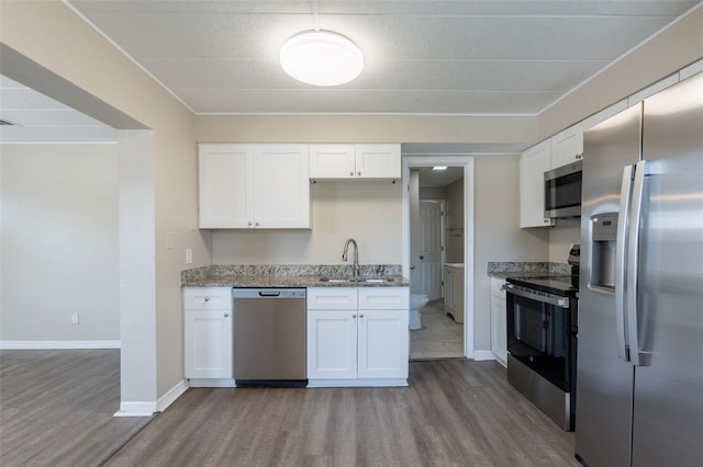 3850 11th Ave S, Saint Petersburg, FL 33711 - kitchen featuring stainless steel appliances, dark wood-style flooring, light stone countertops, white cabinetry, and ornamental molding