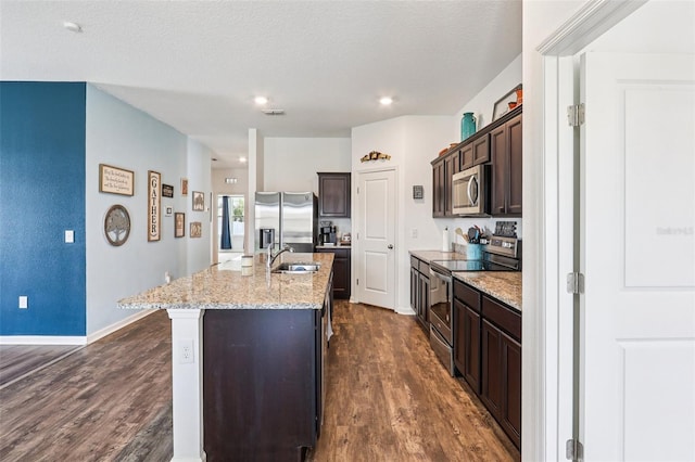 785 Orchid Grove Blvd, Davenport, FL 33837 - kitchen with appliances with stainless steel finishes, dark wood-style floors, dark brown cabinets, an island with sink, and recessed lighting