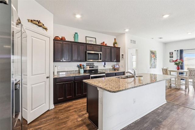 785 Orchid Grove Blvd, Davenport, FL 33837 - kitchen with appliances with stainless steel finishes, dark wood-style flooring, dark brown cabinets, a kitchen island with sink, and recessed lighting