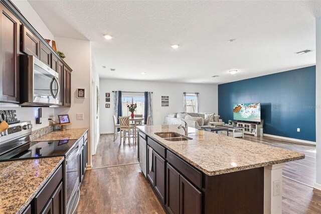 785 Orchid Grove Blvd, Davenport, FL 33837 - kitchen with stainless steel appliances, dark wood-style flooring, dark brown cabinetry, open floor plan, and a textured ceiling