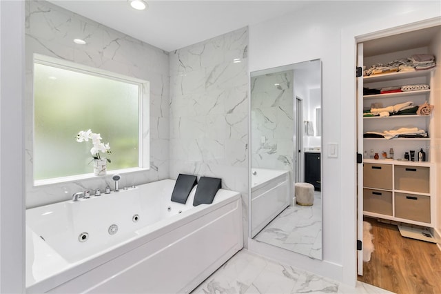 205 Stevenage Dr, Longwood, FL 32779 - bathroom featuring marble look tile flooring, a jetted tub, a spacious closet, and recessed lighting