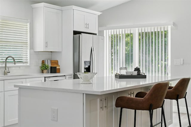 841 Wesson Ct, Casselberry, FL 32707 - kitchen with stainless steel refrigerator with ice dispenser, tasteful backsplash, white cabinetry, a kitchen bar, and light countertops