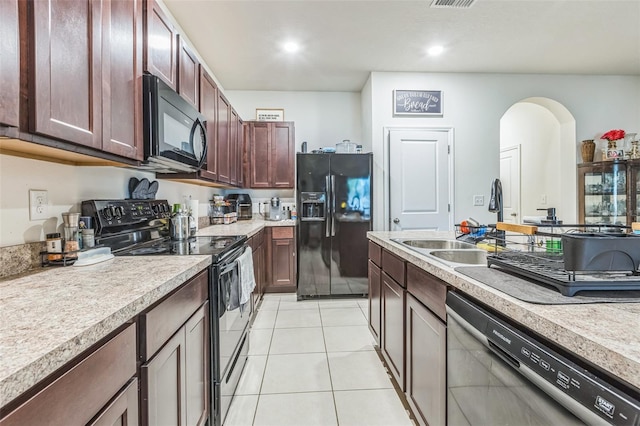 819 Lucent Sands Ct, Brandon, FL 33511 - kitchen with black appliances, light tile patterned floors, light countertops, arched walkways, and recessed lighting