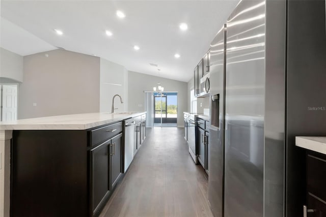 1159 Mountain Flower Ln, Davenport, FL 33837 - kitchen with appliances with stainless steel finishes, vaulted ceiling, a kitchen island with sink, a chandelier, and light wood-type flooring