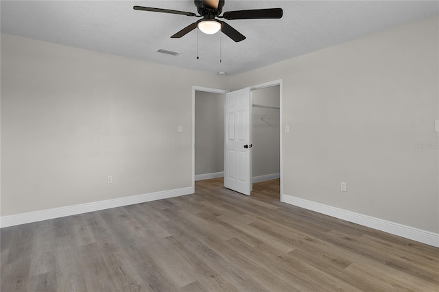 1011 W 13th St, Lakeland, FL 33805 - unfurnished bedroom with wood finished floors, a spacious closet, a textured ceiling, a closet, and ceiling fan