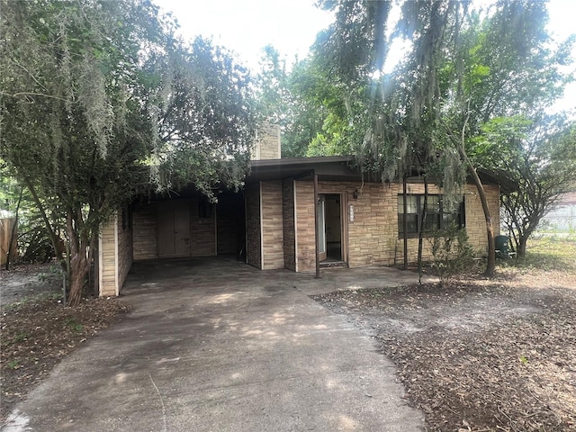 view of front of house featuring concrete driveway and a chimney