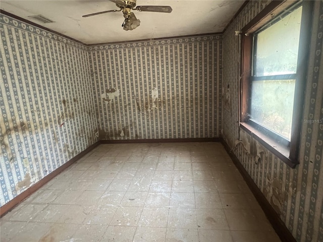 spare room with wallpapered walls, healthy amount of natural light, tile patterned floors, and a ceiling fan