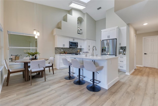 2024 Flaming Arrow Ct, Fern Park, FL 32730 - kitchen with stainless steel appliances, a towering ceiling, a breakfast bar, light countertops, and decorative backsplash