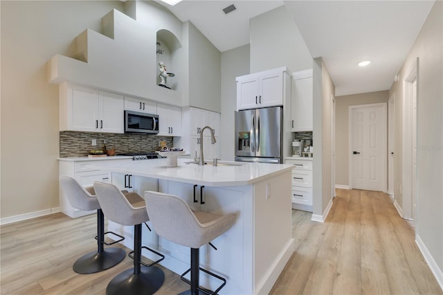 2024 Flaming Arrow Ct, Fern Park, FL 32730 - kitchen featuring appliances with stainless steel finishes, light wood-style floors, a breakfast bar, tasteful backsplash, and a towering ceiling