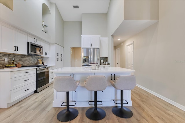 2024 Flaming Arrow Ct, Fern Park, FL 32730 - kitchen with stainless steel appliances, a high ceiling, backsplash, light wood finished floors, and an island with sink