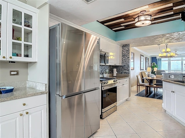 2055 S Atlantic Ave Unit 1410, Daytona Beach Shores, FL 32118 - kitchen featuring appliances with stainless steel finishes, white cabinetry, glass insert cabinets, light tile patterned floors, and ornamental molding