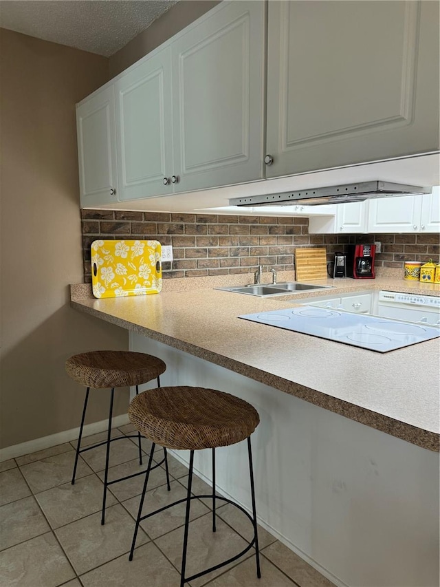 2400 Forest Dr Unit 219, Inverness, FL 34453 - kitchen with backsplash, light tile patterned flooring, a kitchen bar, white cabinets, and light countertops