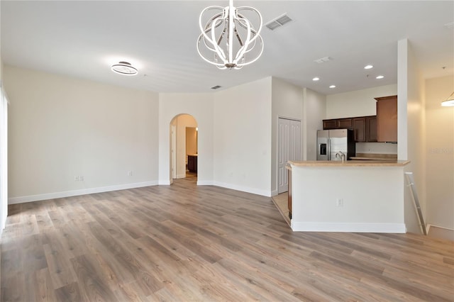 6484 S Goldenrod Rd Unit 41A, Orlando, FL 32822 - kitchen with arched walkways, stainless steel fridge, a chandelier, light wood-type flooring, and open floor plan