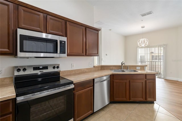6484 S Goldenrod Rd Unit 41A, Orlando, FL 32822 - kitchen featuring appliances with stainless steel finishes, a peninsula, light countertops, and hanging light fixtures