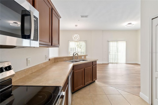 6484 S Goldenrod Rd Unit 41A, Orlando, FL 32822 - kitchen featuring appliances with stainless steel finishes, brown cabinets, hanging light fixtures, and light countertops