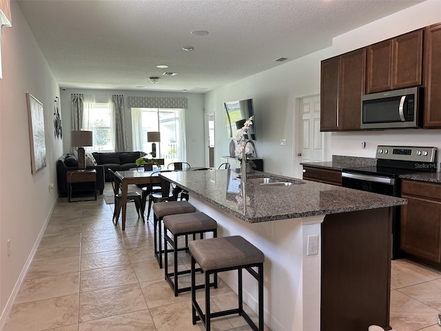 2824 Neverland Dr, New Smyrna Beach, FL 32168 - kitchen featuring stainless steel appliances, healthy amount of natural light, a breakfast bar, open floor plan, and a textured ceiling