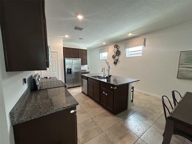 2824 Neverland Dr, New Smyrna Beach, FL 32168 - kitchen with stainless steel appliances, a kitchen island with sink, dark brown cabinets, light marble finish floors, and recessed lighting