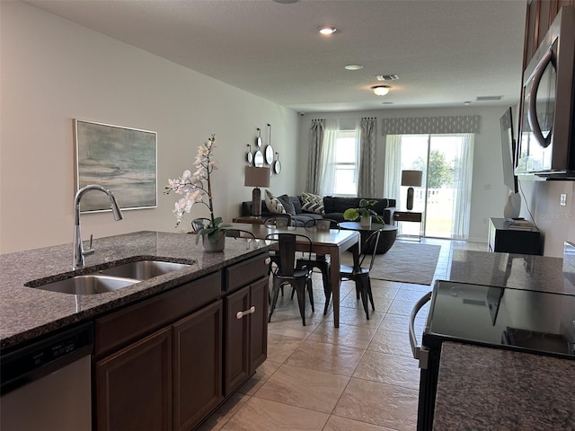 2824 Neverland Dr, New Smyrna Beach, FL 32168 - kitchen with stainless steel appliances, open floor plan, dark stone countertops, dark brown cabinetry, and recessed lighting
