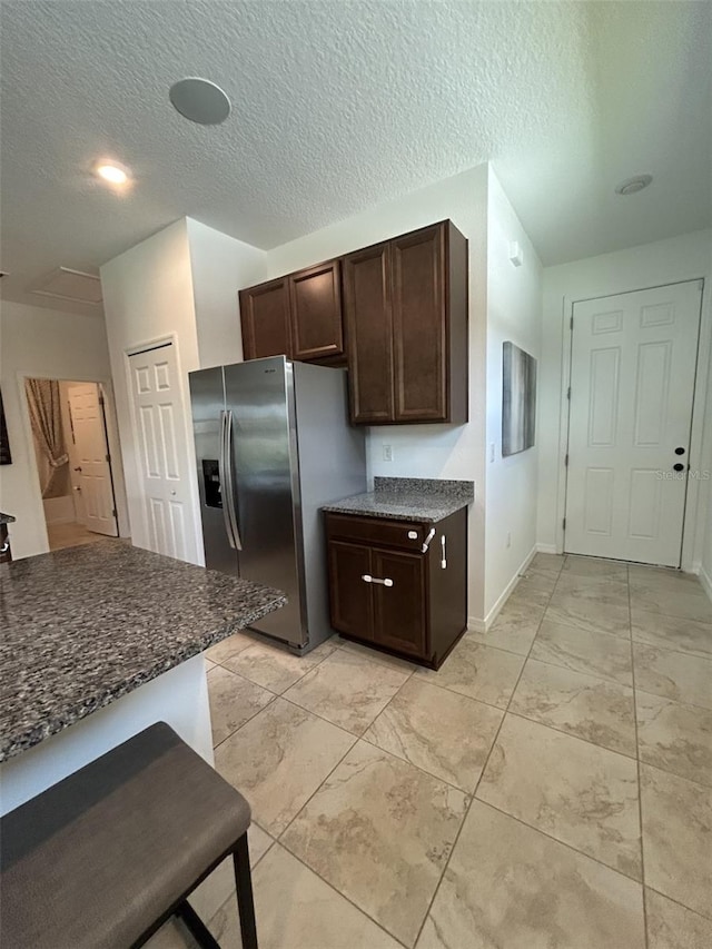 2824 Neverland Dr, New Smyrna Beach, FL 32168 - kitchen with stainless steel refrigerator with ice dispenser, dark brown cabinets, light marble finish floors, and a textured ceiling