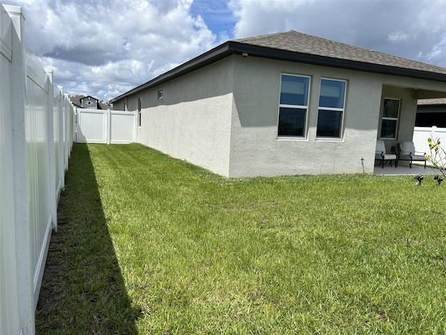 2824 Neverland Dr, New Smyrna Beach, FL 32168 - view of side of home featuring a fenced backyard, stucco siding, a patio, and roof with shingles