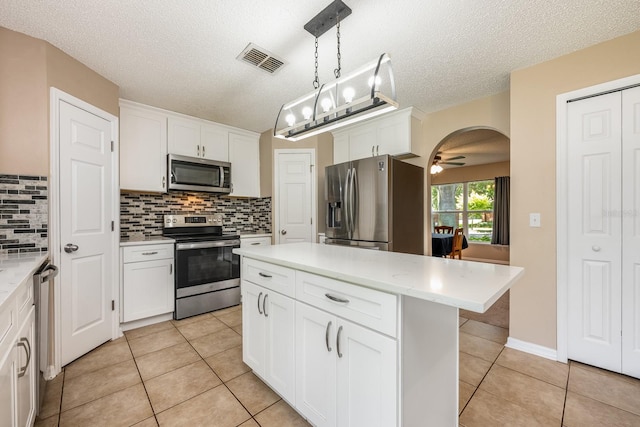 100 Monterey Oaks Dr, Sanford, FL 32771 - kitchen featuring appliances with stainless steel finishes, arched walkways, decorative backsplash, light tile patterned floors, and light countertops
