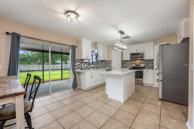 100 Monterey Oaks Dr, Sanford, FL 32771 - kitchen featuring appliances with stainless steel finishes, tasteful backsplash, a kitchen island, light countertops, and a textured ceiling
